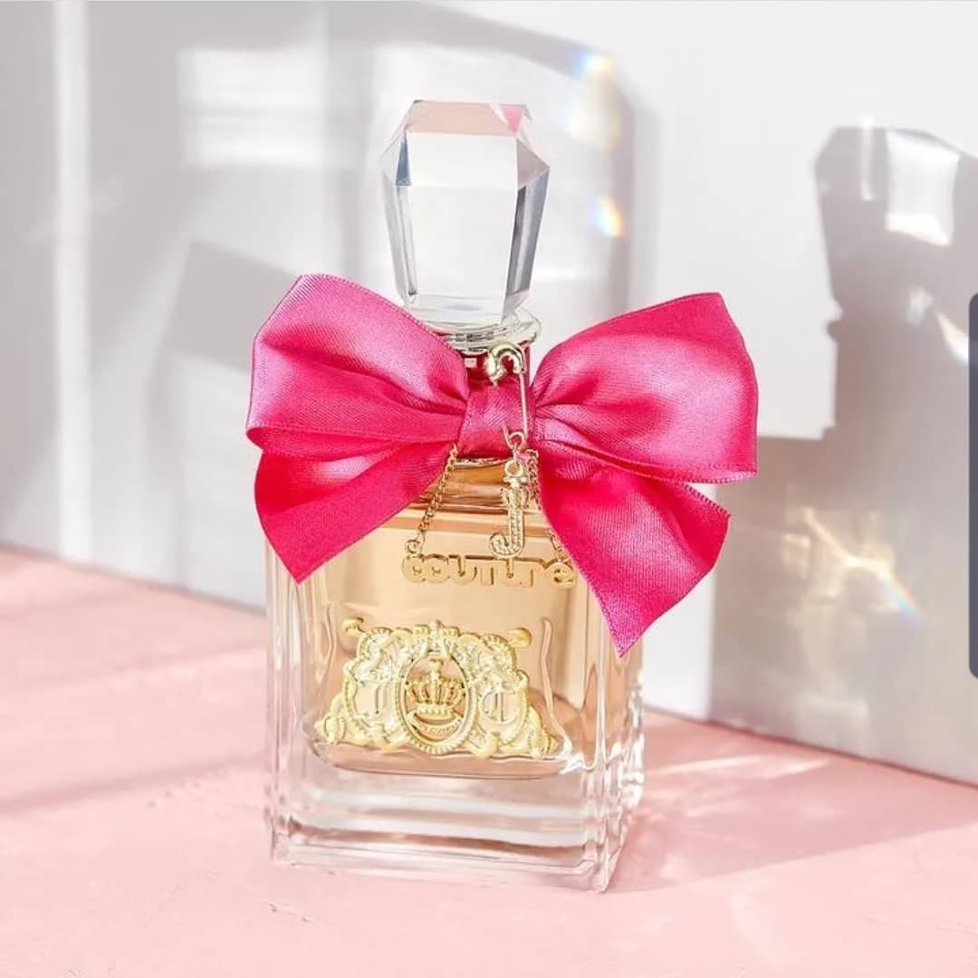 عطر ویوا لا جوسی زنانه، رنگ شفاف، صورتی و طلایی، جنس شیشه و ساتن، بطری مستطیلی با پاپیون