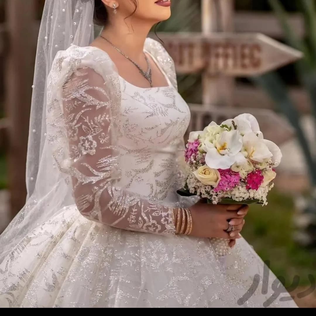 لباس عروس اکلیلی با شنل و تور، رنگ سفید، جنس ساتن، طرح گلدوزی، بلند، یقه خشتی، آستین بلند، پفی