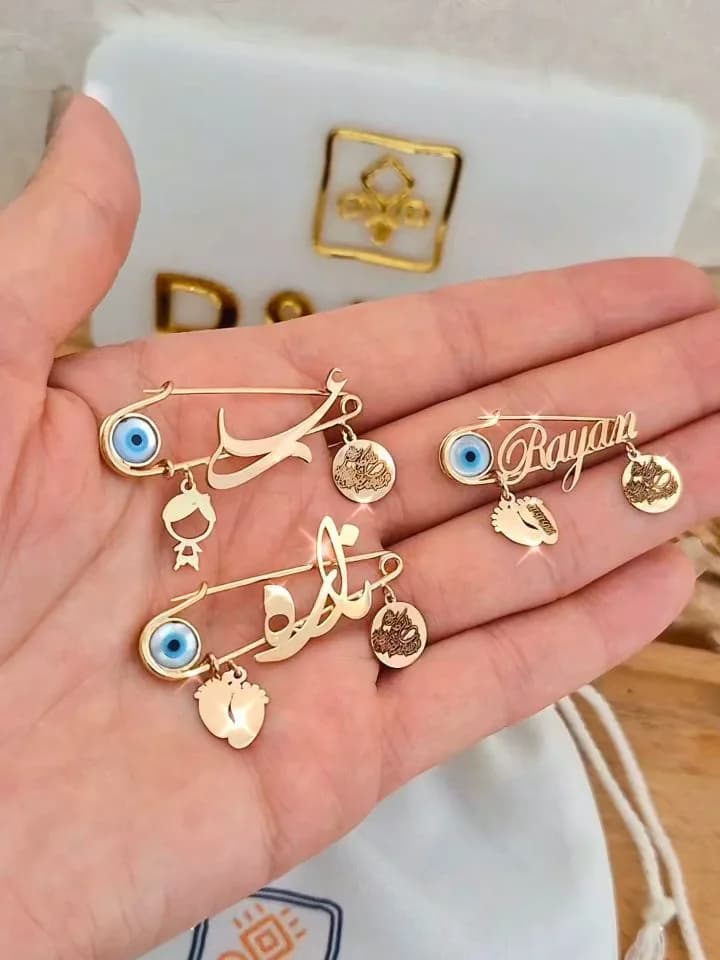 سنجاق سینه طلای اسم کودک، رنگ طلایی و آبی، جنس فلز، مدل سنجاق با آویز نام و چشم