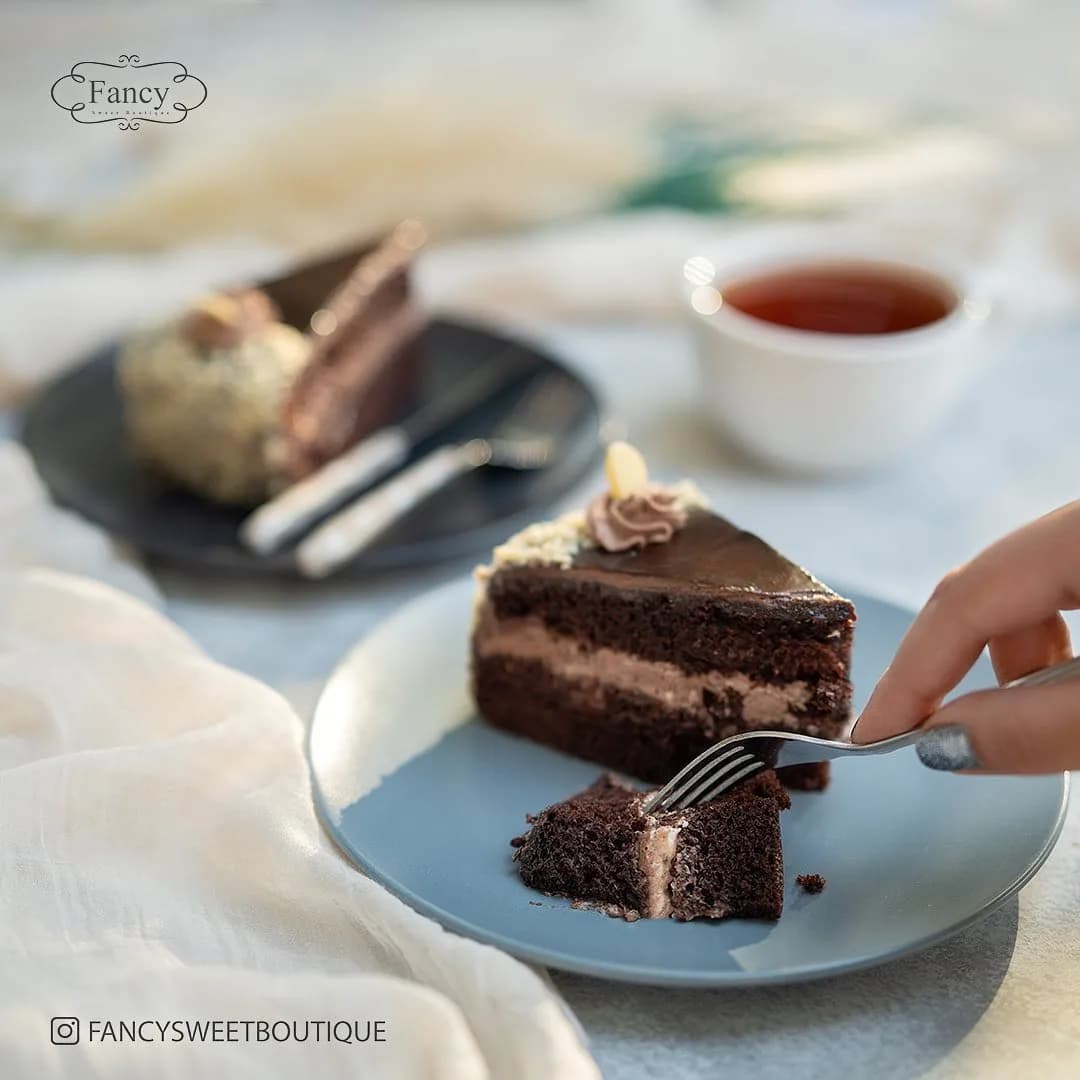 کیک شکلاتی با خامه و بادام فنسی، رنگ قهوهای تیره و کرم، مثلثی، لایهای