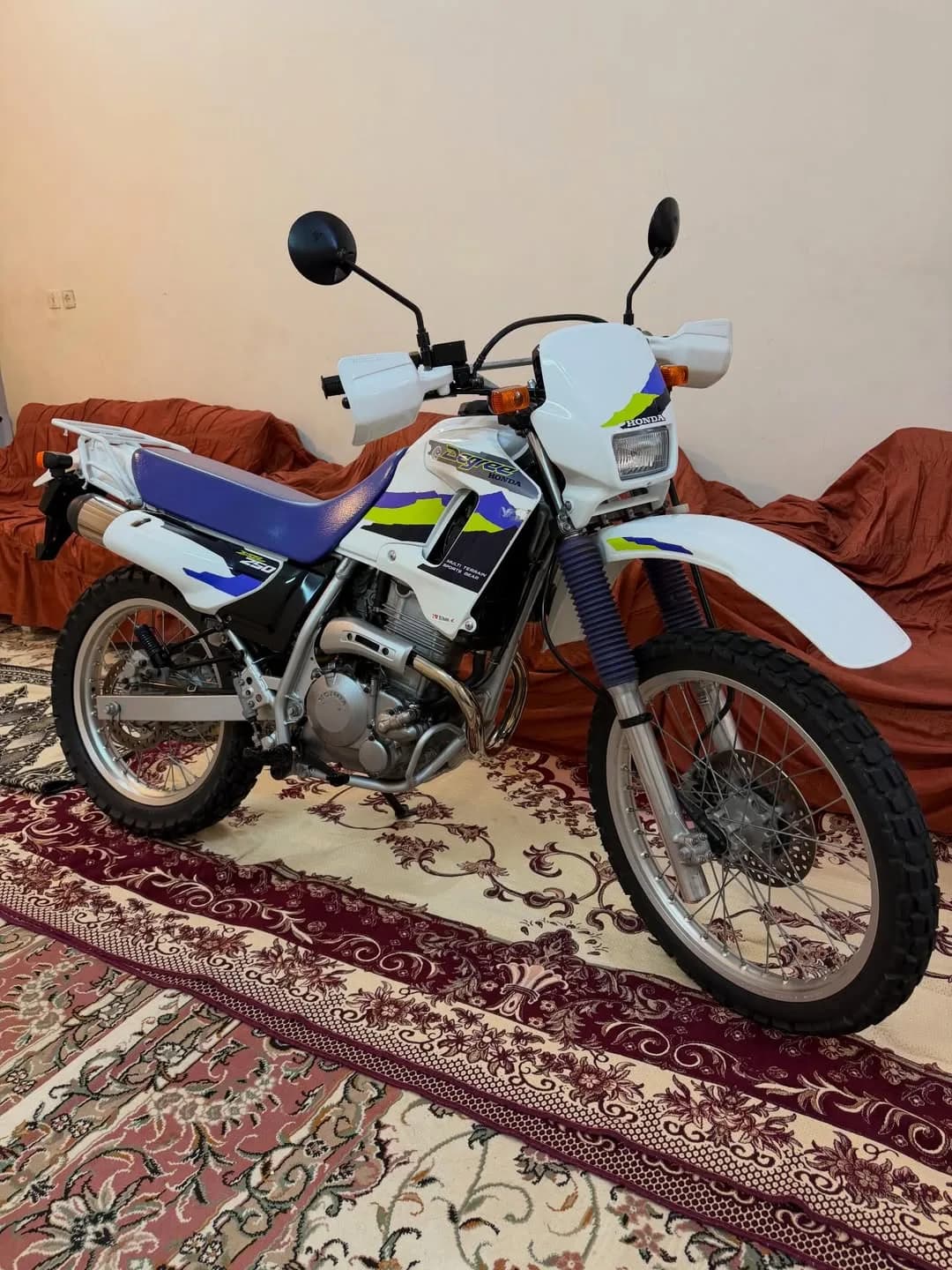 موتورسیکلت هوندا AX-1 مدل ۱۹۹۵، رنگ سفید، آبی و زرد، جنس فلز و پلاستیک، کراس