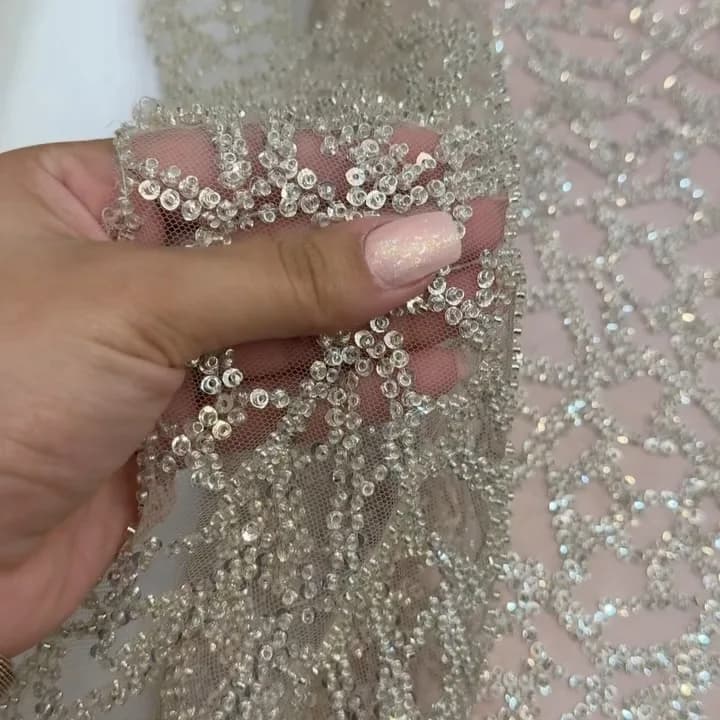 پارچه مجلسی کار شده سنگ دوزی، رنگ نقره‌ای و سفید، جنس توری، طرح هندسی، پولک‌دوزی