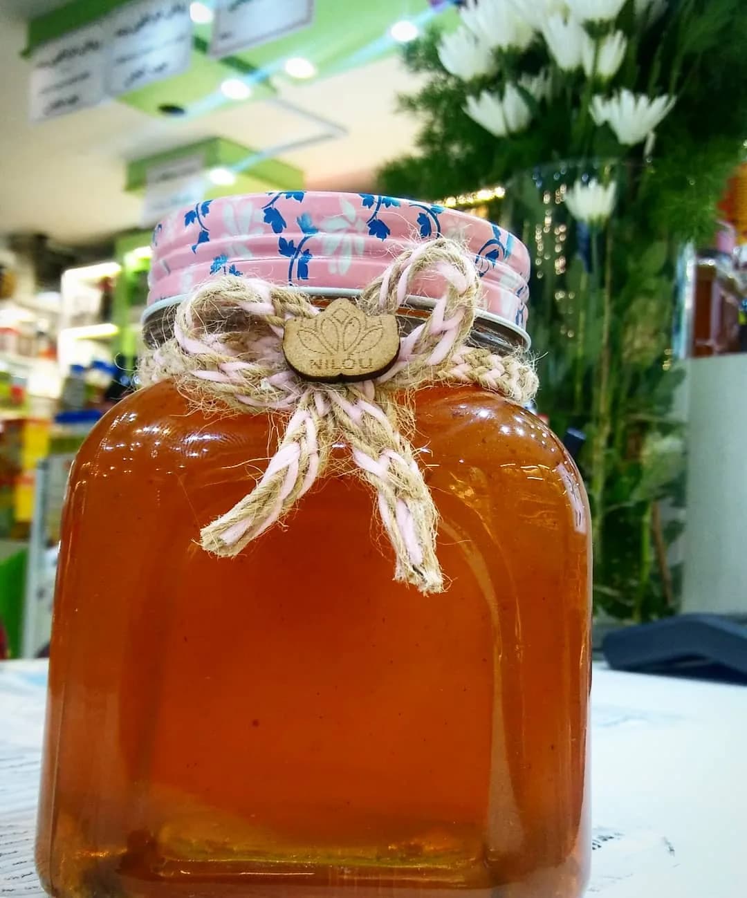عسل طبیعی درمانی تکاب نیلو، رنگ کهربایی و صورتی، جنس شیشه، طرح گل‌دار، شیشه‌ی مکعبی