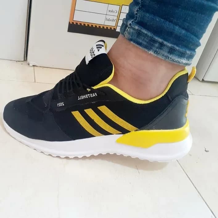 کتانی اسپرت مردانه، رنگ مشکی، زرد و سفید، جنس چرم مصنوعی و پلاستیک، طرح راهراه، کتانی بندی ورزشی