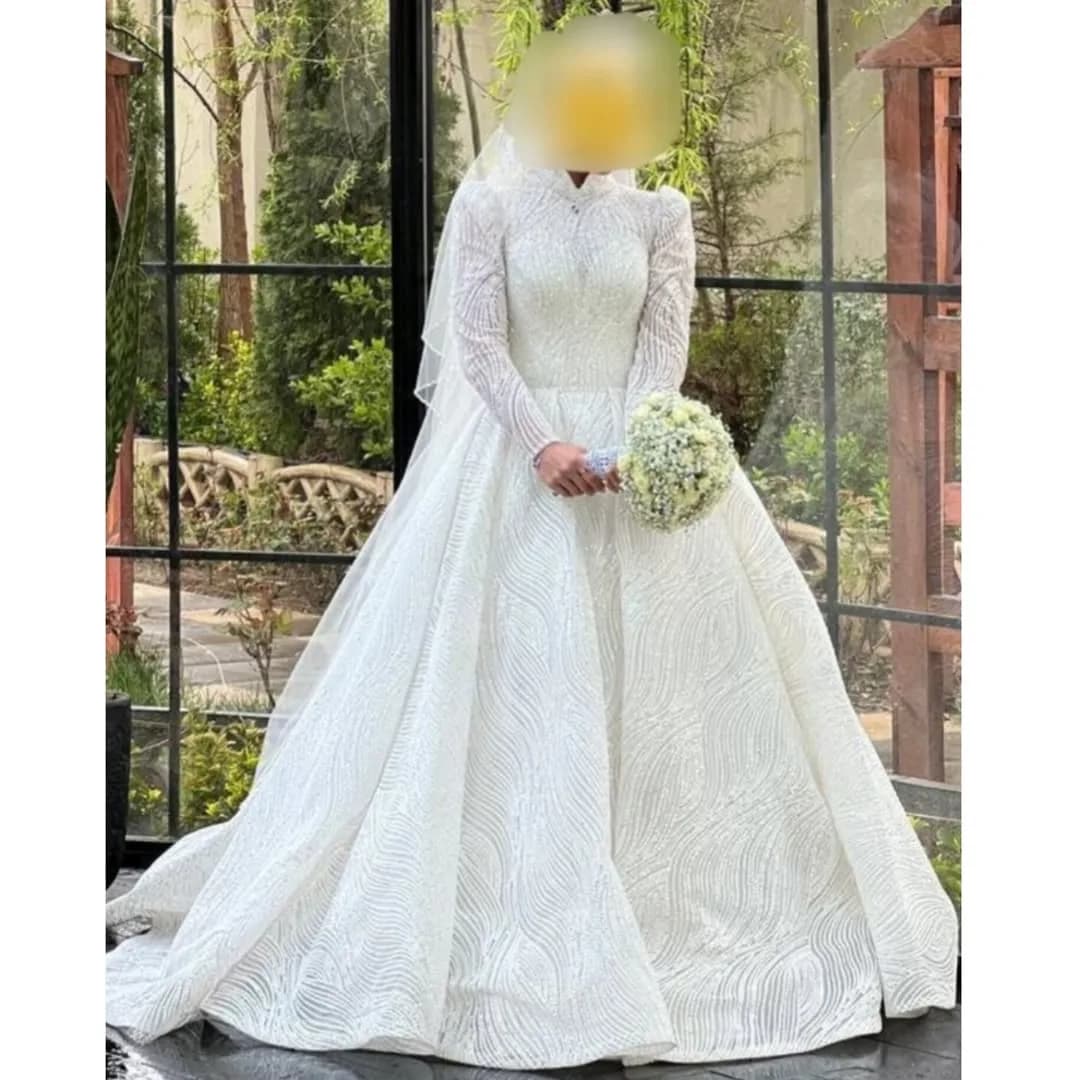 لباس عروس پرنسسی دنبالهدار سایز ۳۶ تا ۳۸، رنگ سفید، جنس توری، طرح گلدوزی، بلند، یقه بسته، آستین بلند، پفدار
