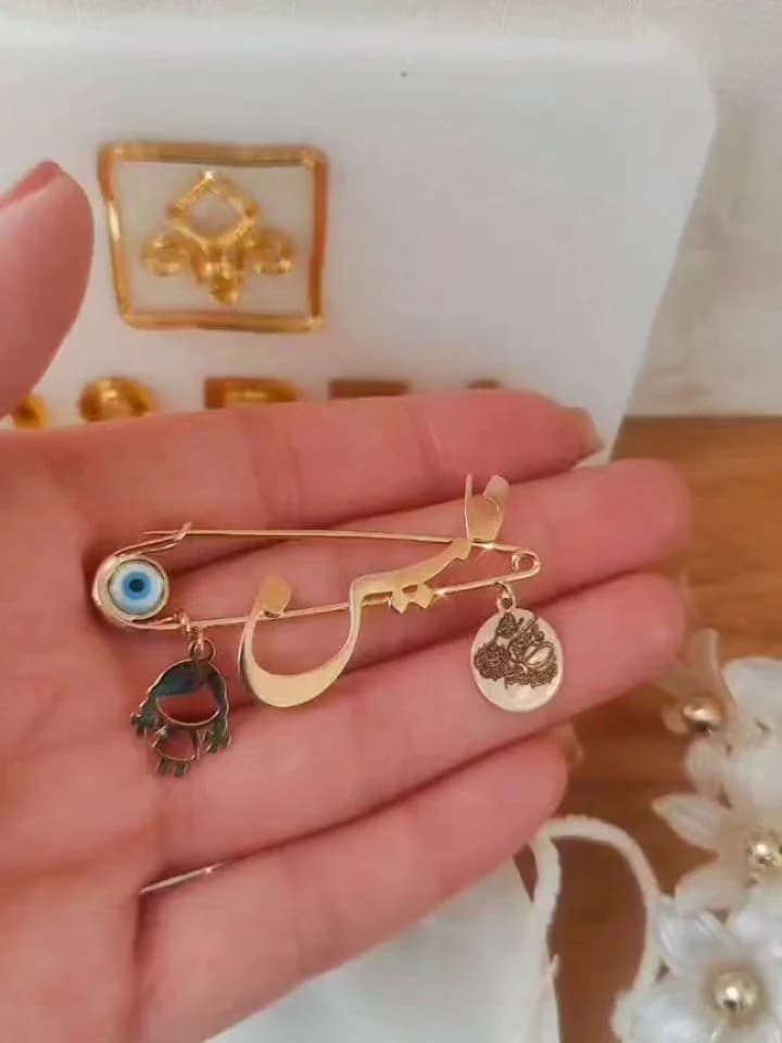 سنجاق کودک اسم، رنگ طلایی و آبی، جنس فلز، سنجاق سینه با پلاک و چشم