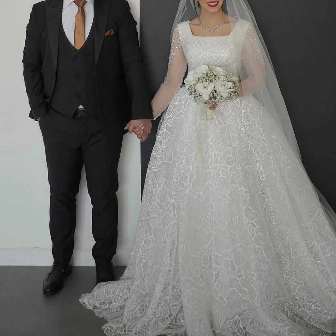 لباس عروس مزون‌دوز با ژپون ۵ فنره، رنگ سفید، جنس توری، طرح گلدوزی، بلند، آستین بلند، کلوش