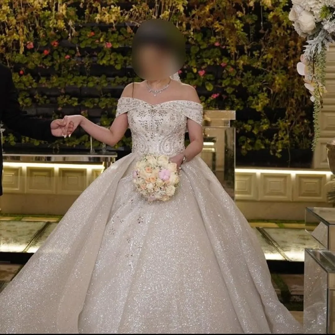 لباس عروس عربی سنگدوزی با سنگ اتریشی، رنگ سفید، جنس ساتن و پولک، بلند، یقه قایقی، بدون آستین، پفی