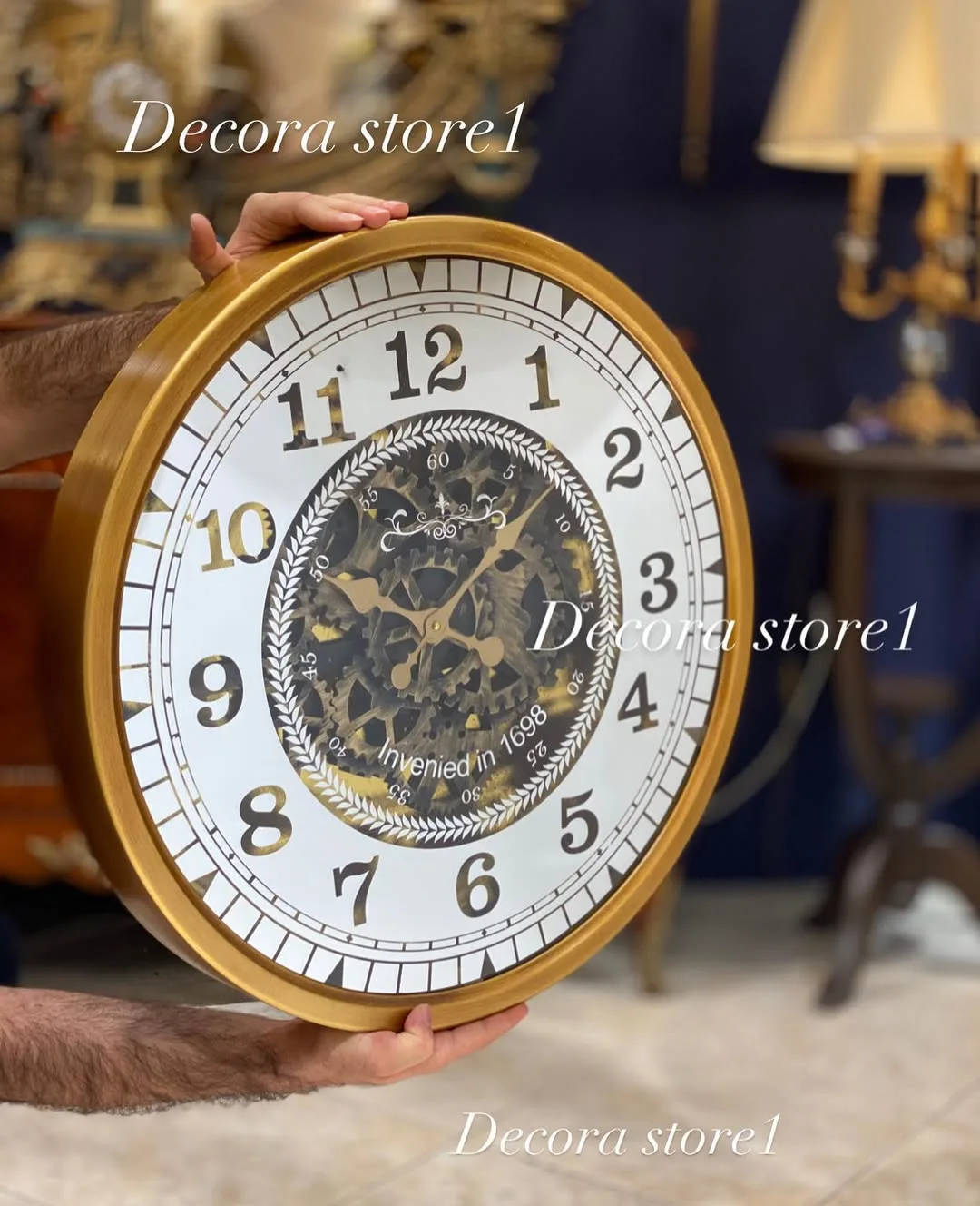 ساعت دیواری آینه‌ای چرخ‌دنده، رنگ طلایی و سفید، جنس فلز و شیشه، طرح هندسی، گرد بزرگ اعداد رومی