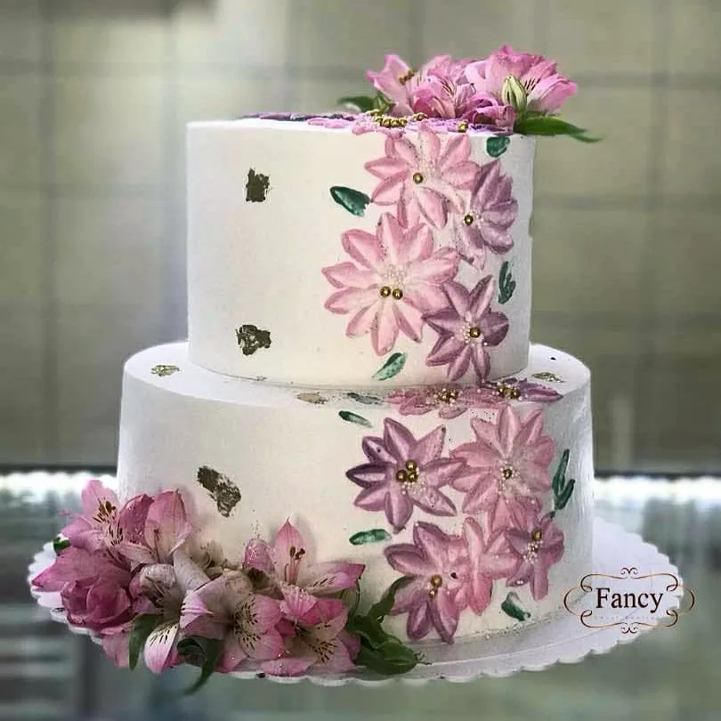 کیک تولد دو طبقه، رنگ سفید، صورتی و بنفش، طرح گلدار، استوانه‌ای