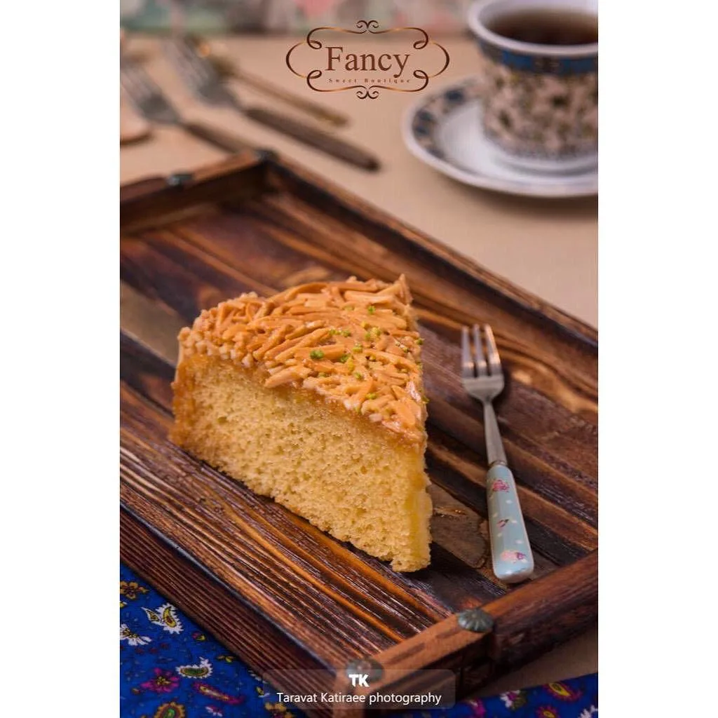 کیک ملکه بادام فنسی، رنگ طلایی و قهوه‌ای، برش کیک قاچ‌خورده