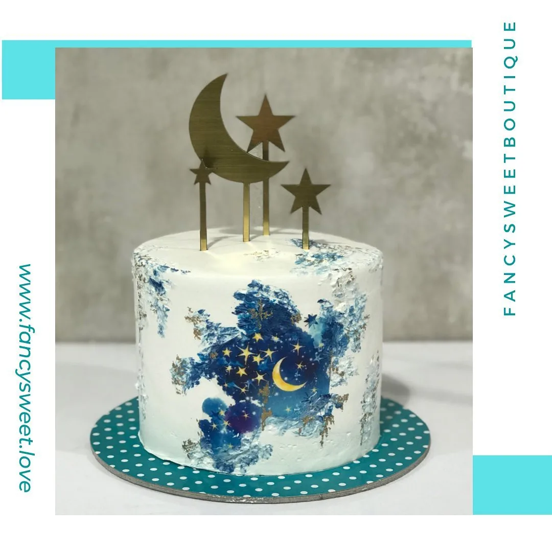کیک تولد طرح آسمان، رنگ سفید، آبی و طلایی، جنس خامه و فلز، گرد طبقه متوسط