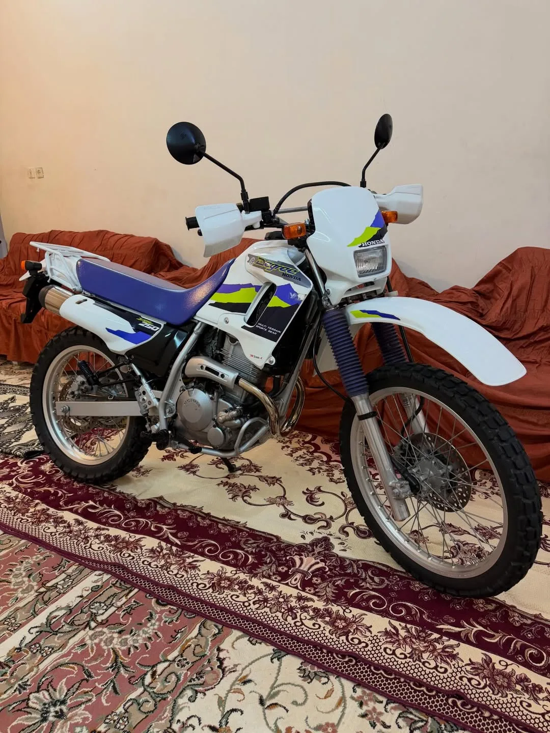 موتورسیکلت هوندا AX-1 مدل ۱۹۹۵، رنگ سفید، آبی و زرد، جنس فلز و پلاستیک، کراس