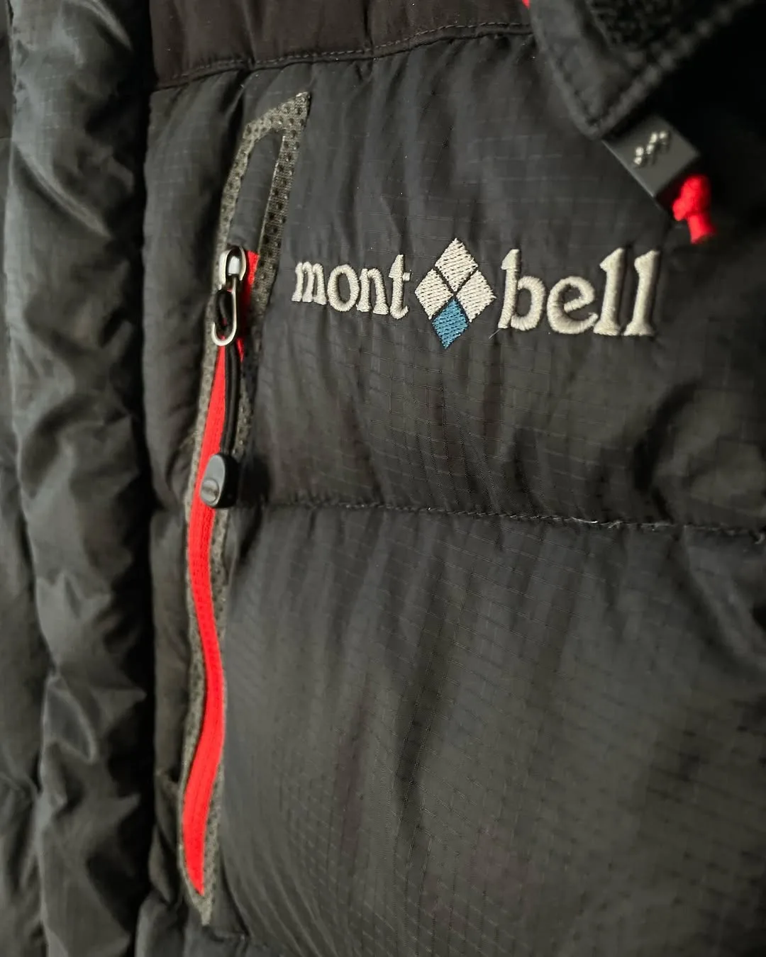 کاپشن Mont-bell، رنگ مشکی و قرمز، جنس پلاستیک، کوتاه جیبدار زیپدار